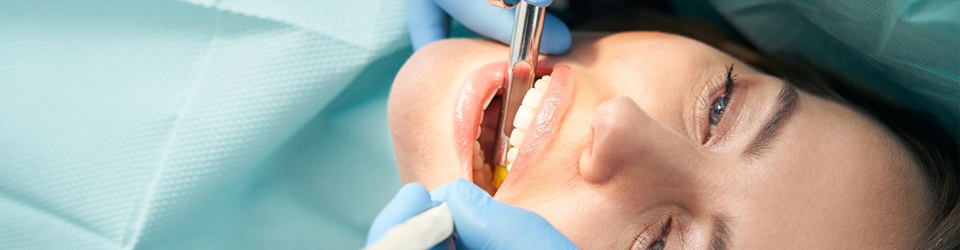 gloved hand injecting syringe into woman's mouth